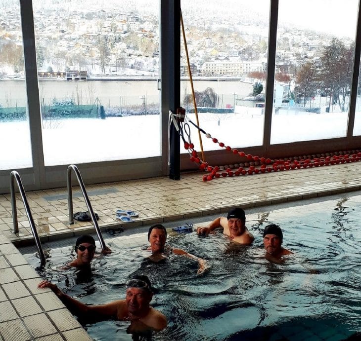 Photos des nageurs dans la piscine avec la vue sur la ville de Gérardmer enneigée au travers es baies vitrées